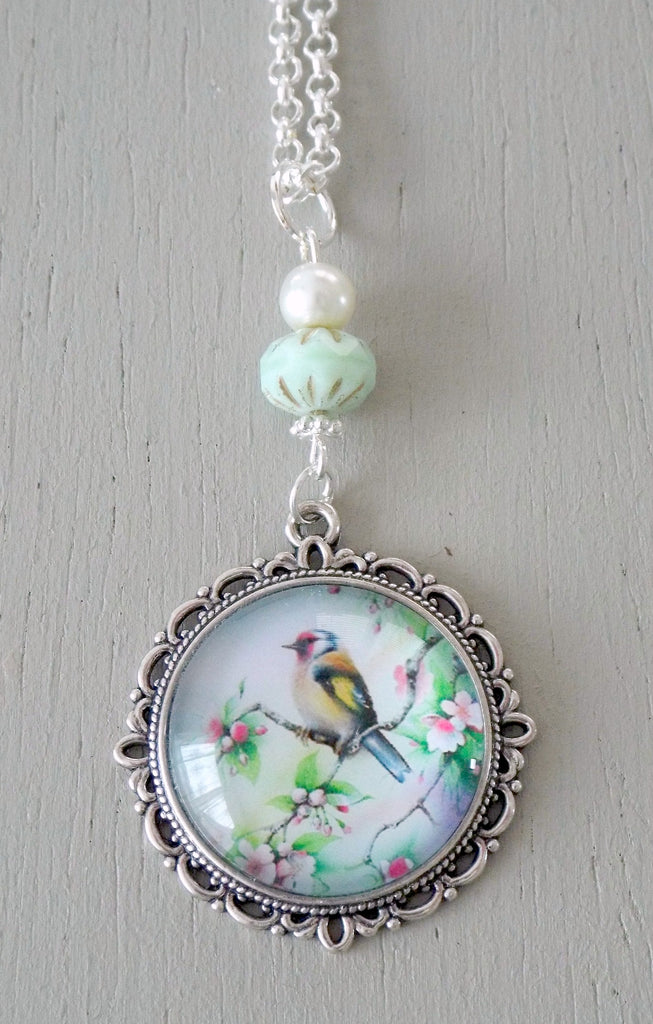 Pendant with 25mm neutral yellow, green bird focal, ornate setting, mint & ivory beads